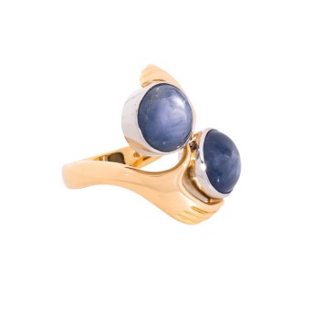 Extravaganter Damenring. Bes. mit 2 feinen Sternsaphir-Cabochóns zus. 16,0 cts. mit feinem Asterismus.